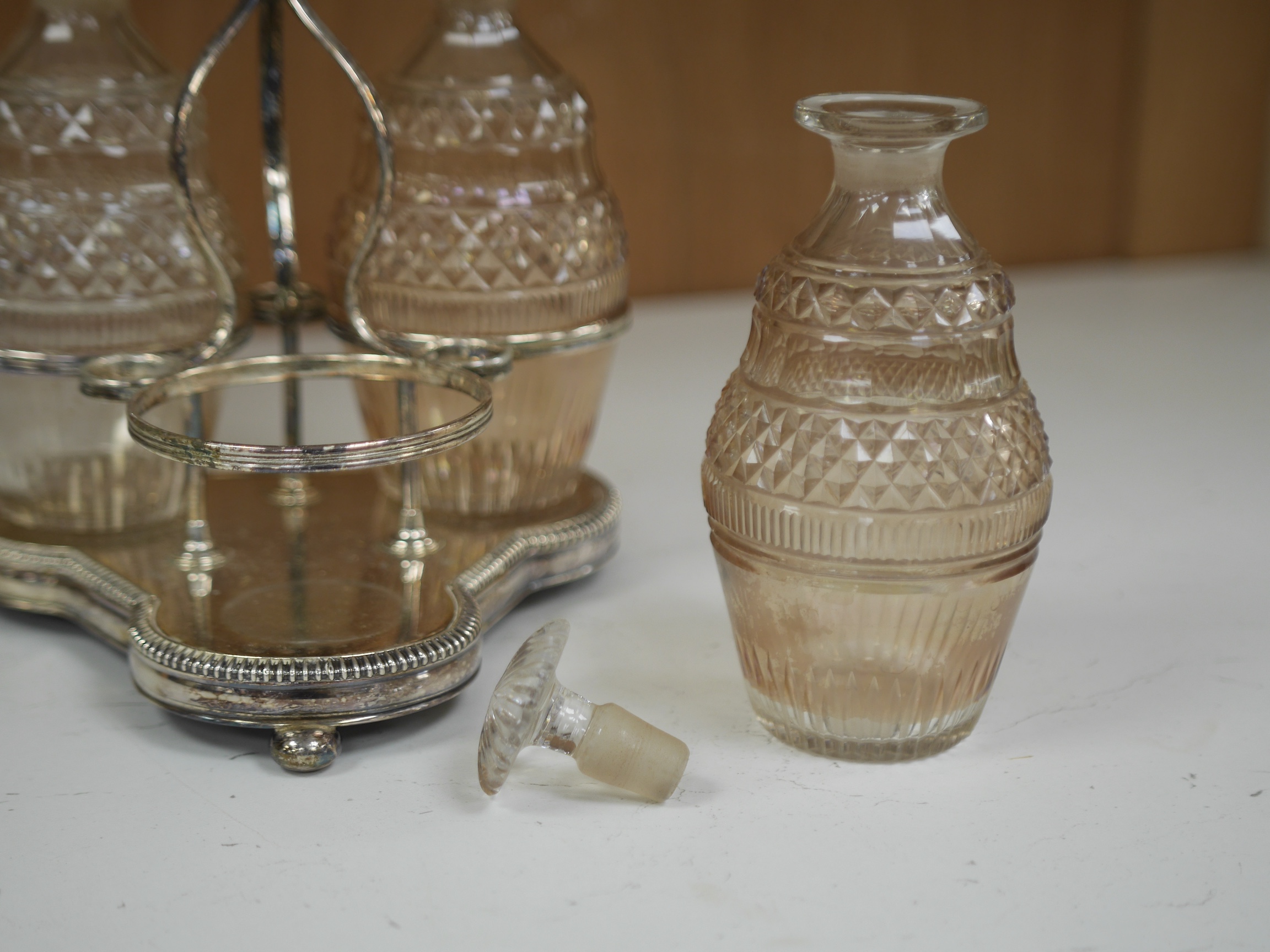 A cased silver plated three bottle liqueur stand, a cranberry decanter, sugar shaker and jam stand together with a green glass shaker, stand 27cm high (5). Condition - all items in good condition, box in need of a clean